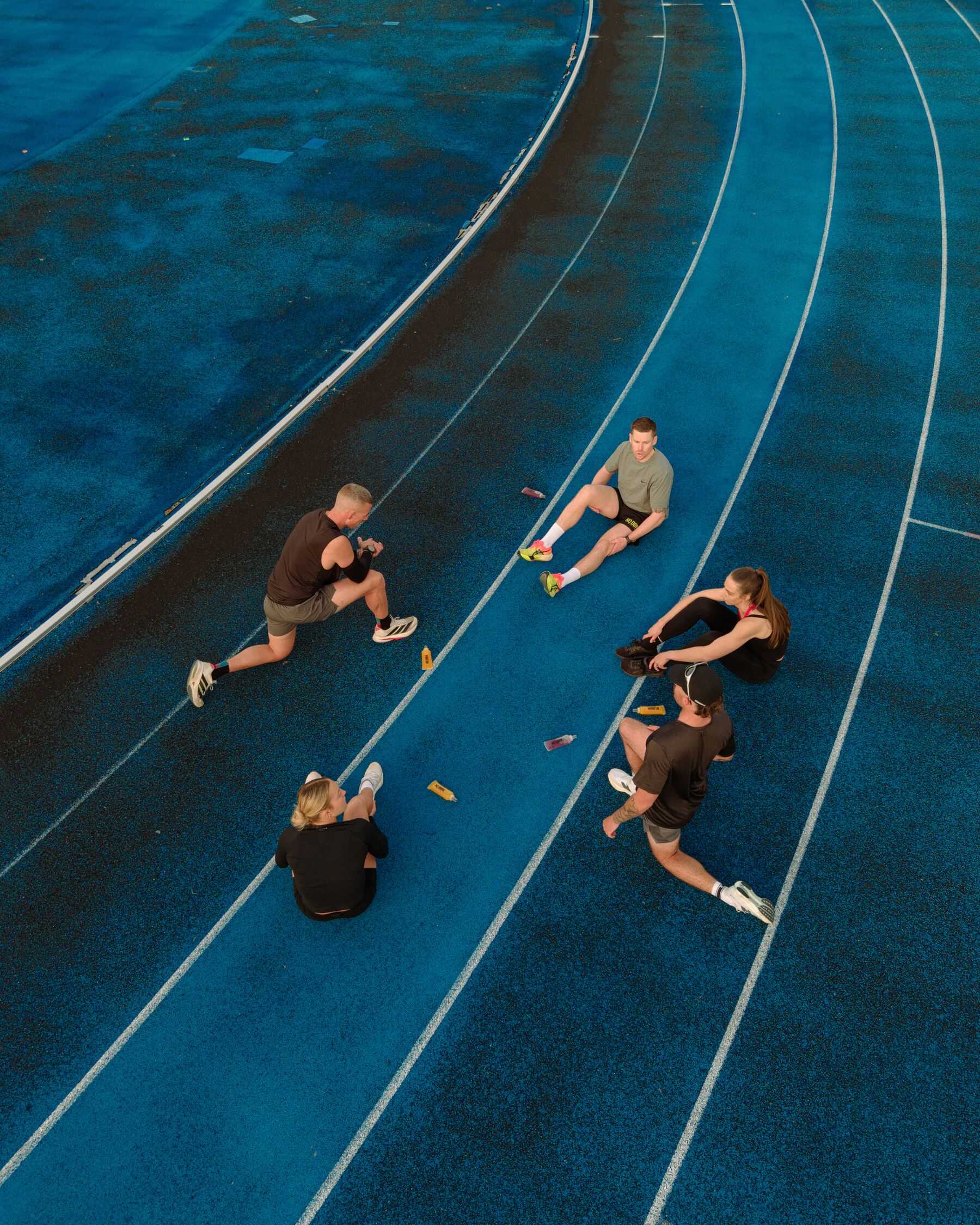 Overhead view of runners stretching across the lanes of a blue athletics track