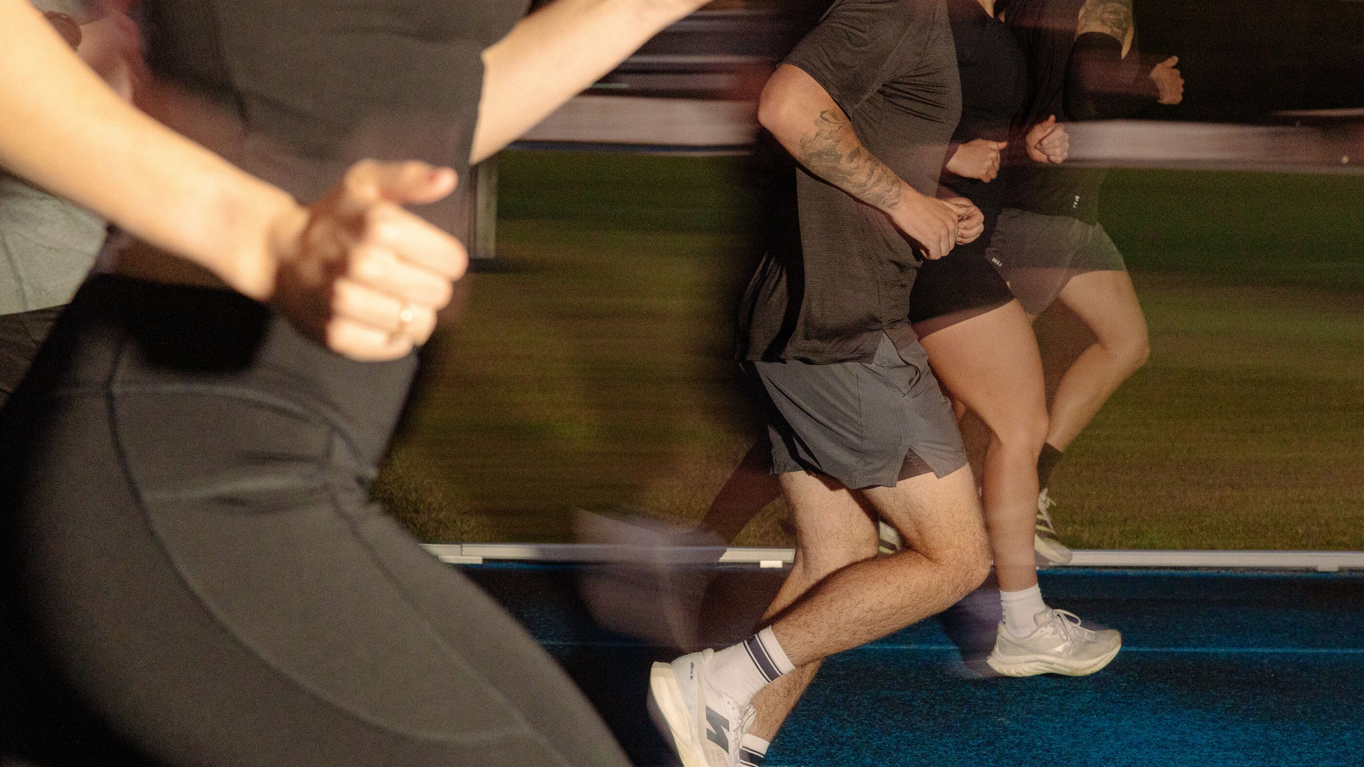 Four runners mid-stride on a blue athletics track, panned so the background blurs